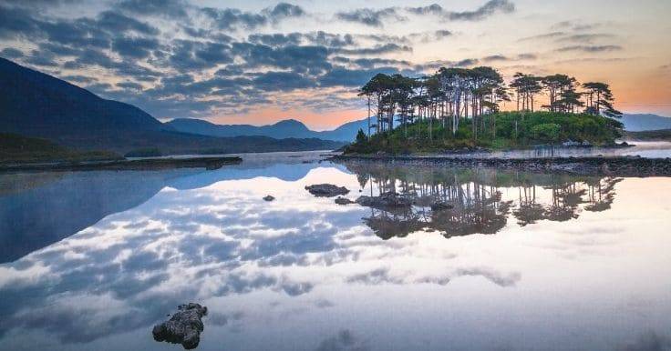 Puesta de sol y nubes grises sobre un lago y una isla, cursos de inglés en Galway