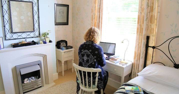 una mjuer estudiando con portatil en un dormitorio una casa de familia