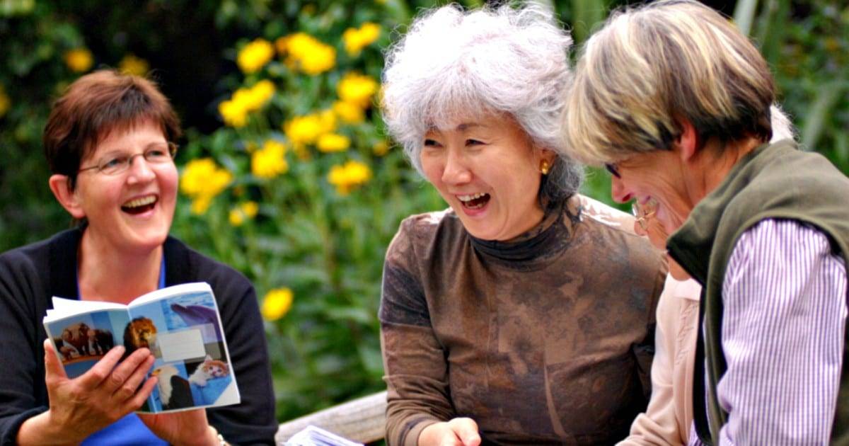 tres mujeres mayores de 50 años reindo en un jardin