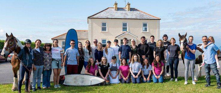 Familias con tablas de surf y caballos frente a su escuela de inglés en Irlanda