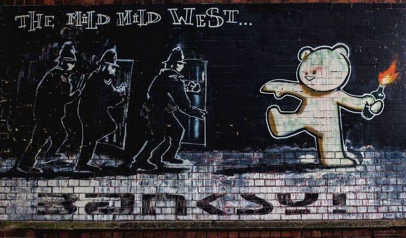 Banksy Graffiti de 3 policías antidisturbios acercándose a un oso con un cóctel molotov