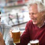 tres adultos riéndose mientras beben una pinta de cerveza
