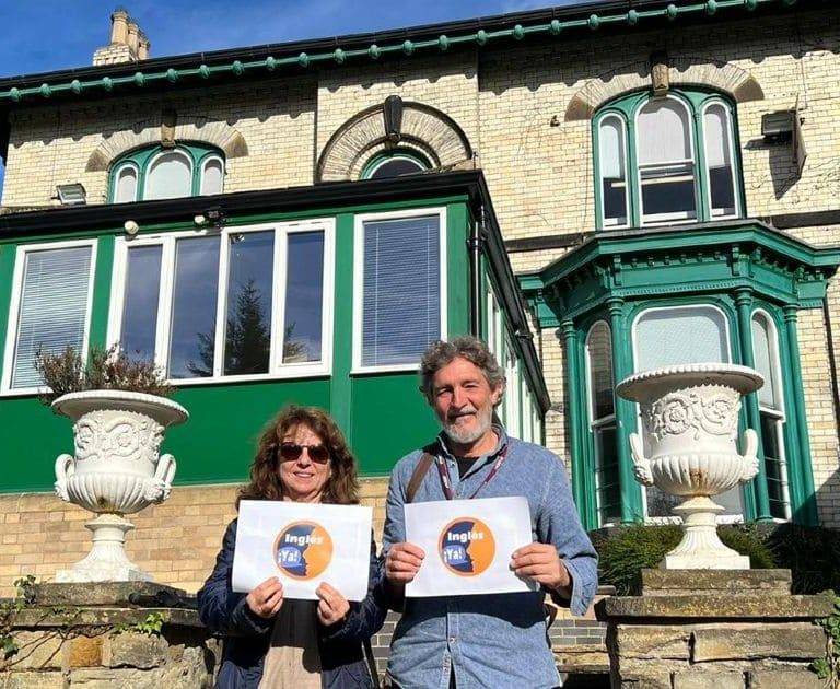 dos adultos con logo de Inglés Ya con la escuela de inglés al fondo