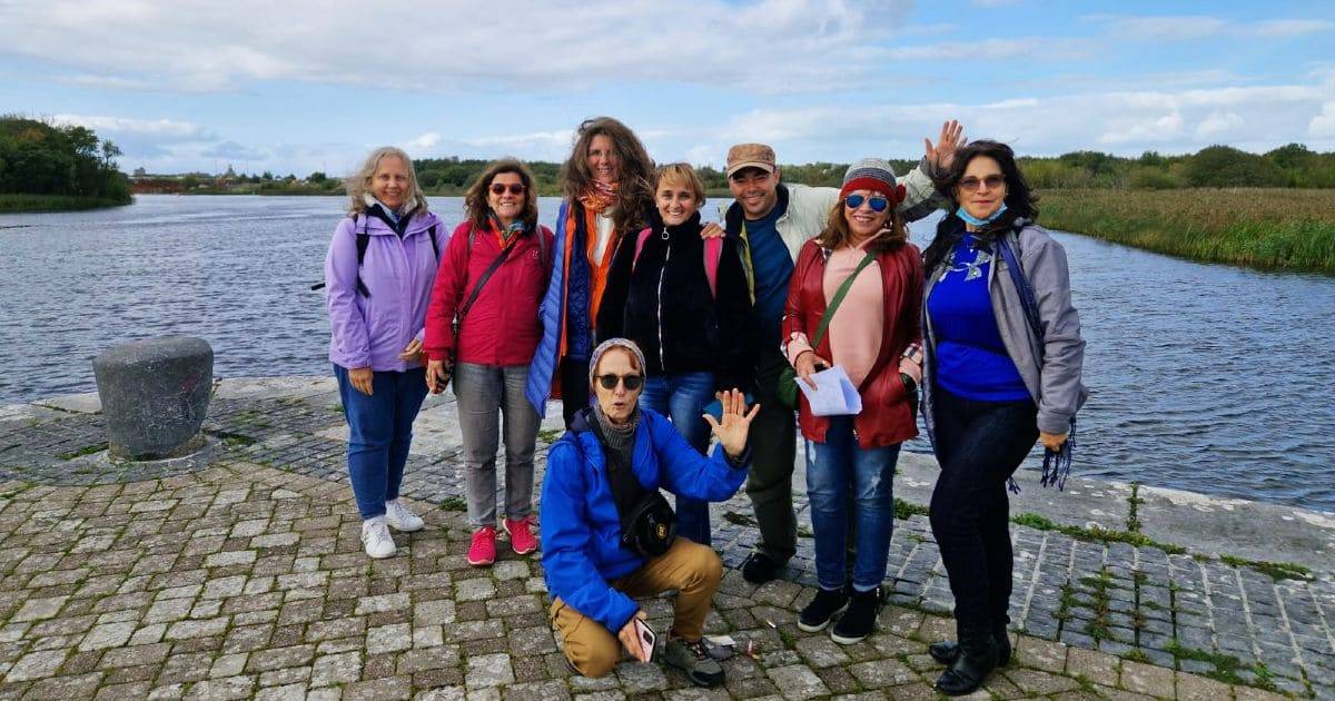 Grupo de estudiantes de inglés mayores de 50 años, de excursión posando para una foto con el río Corrib (Galway) al fondo