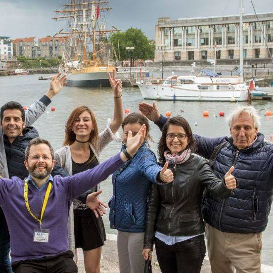 seis adultos mayores de 45 años saludando con el puerto de Bristol de fondo